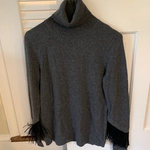 Cashmere turtleneck with fringe at sleeves.